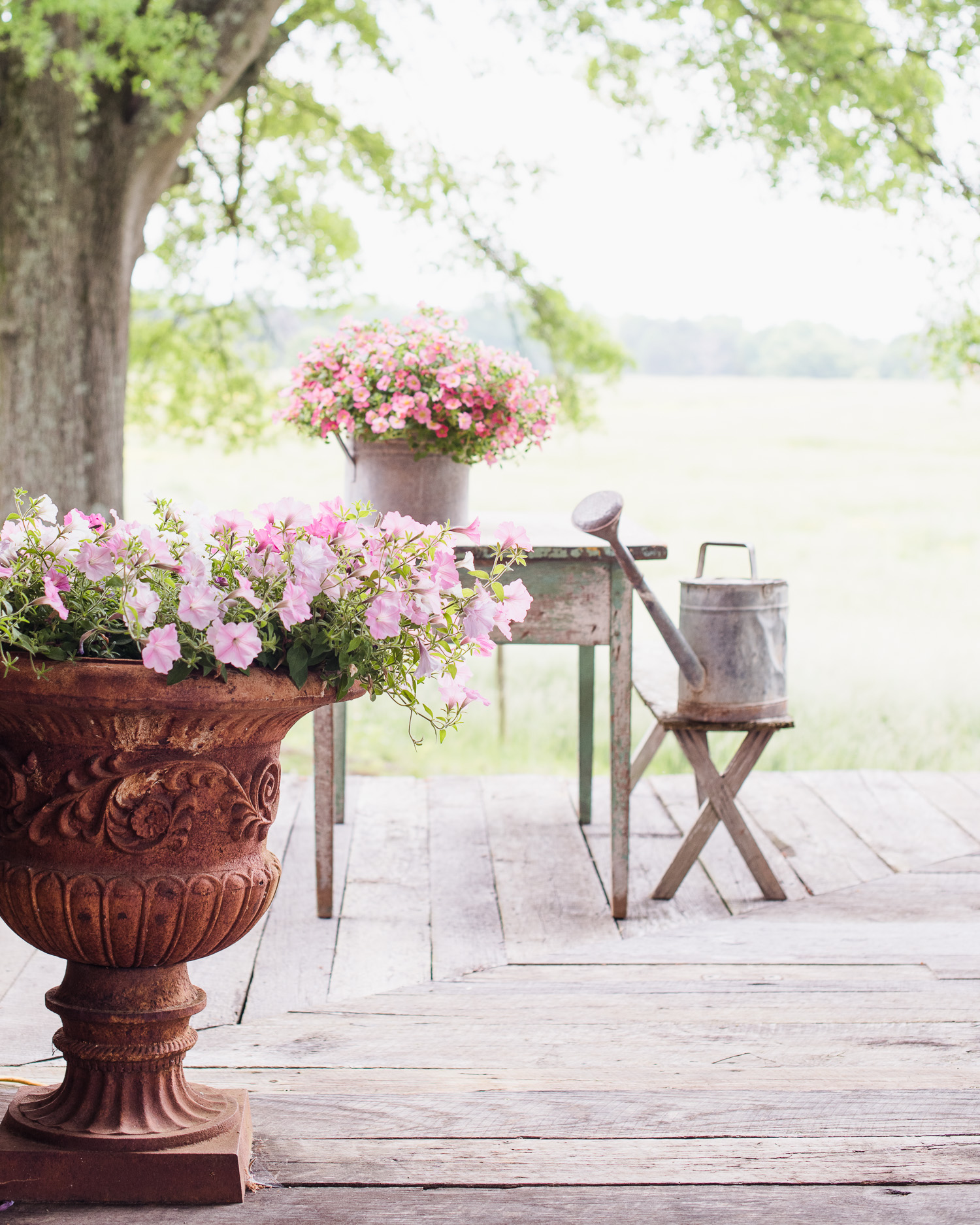 Country Living Spring Porch Decor | Antique Table, watering can, urn with flowers