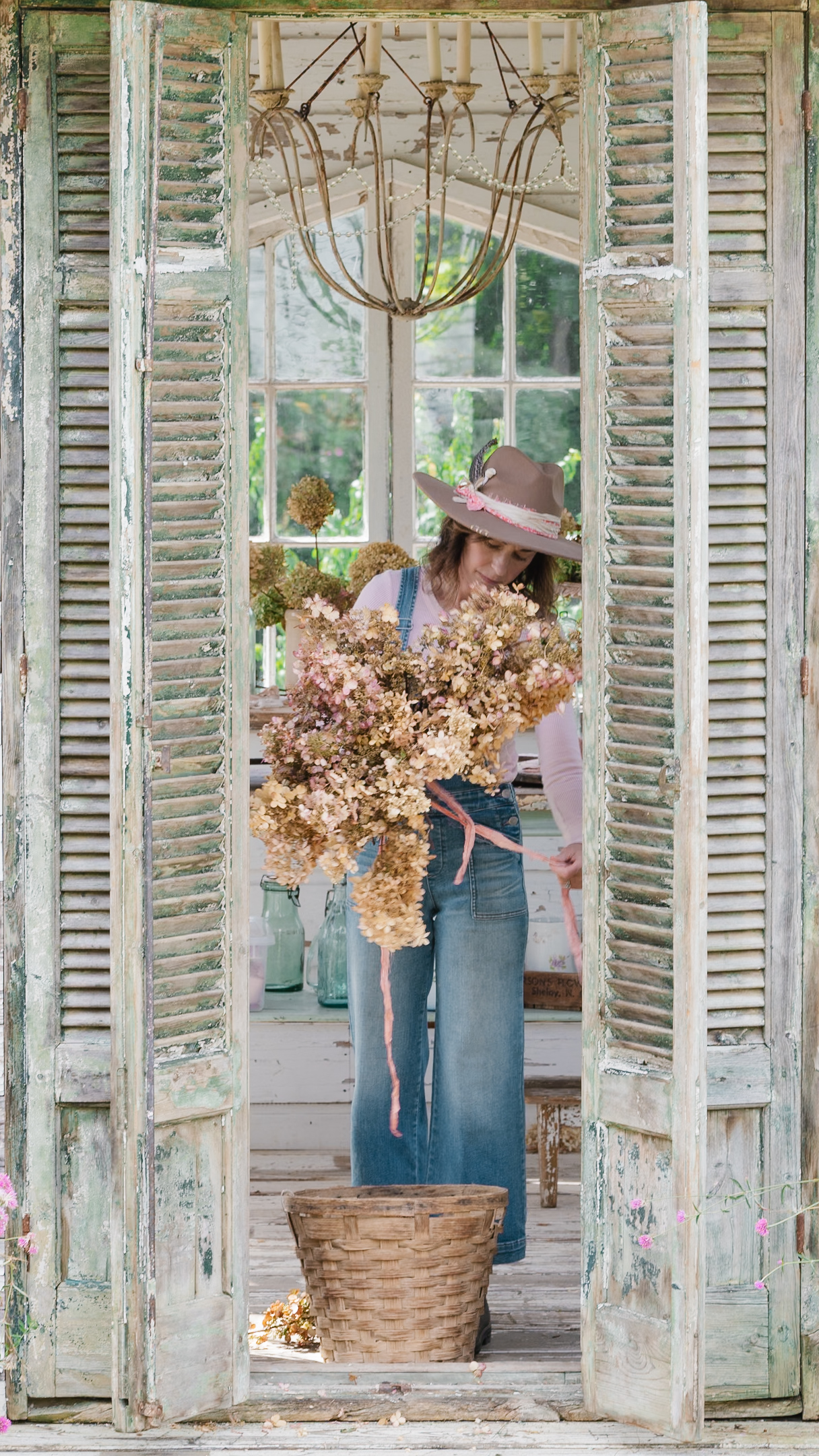 A girl holding standing in a flower house holding dried hydrangeas